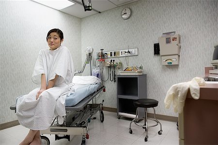 Low angle view of a young woman sitting on an examination table Stock Photo - Premium Royalty-Free, Code: 640-01355713