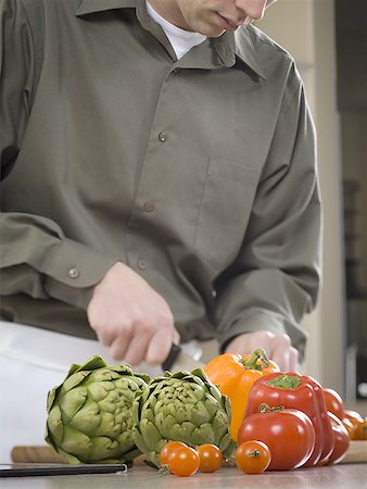 Close-up of a young man cutting vegetables Stock Photo - Premium Royalty-Free, Code: 640-01355787