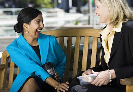 Two businesswomen sitting on a bench and talking Stock Photo - Premium Royalty-Free, Code: 640-01356260
