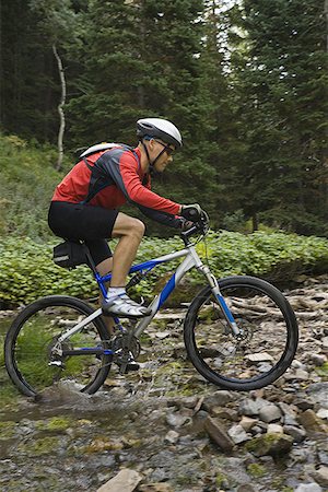 Profile of a mature man cycling over a creek Stock Photo - Premium Royalty-Free, Code: 640-01356475