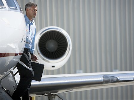 Profile of a businessman exiting an airplane Stock Photo - Premium Royalty-Free, Code: 640-01356666