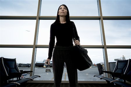 Low angle view of a mid adult woman standing at an airport lounge Stock Photo - Premium Royalty-Free, Code: 640-01356761