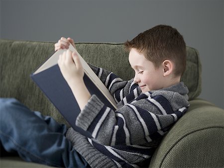 Profile of a boy reading a book on a couch Stock Photo - Premium Royalty-Free, Code: 640-01357097