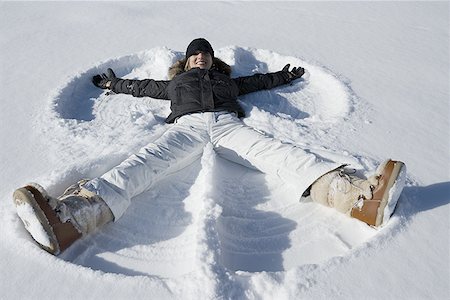 simsearch:6108-06167383,k - High angle view of a young woman lying in snow making a snow angel Stock Photo - Premium Royalty-Free, Code: 640-01357755