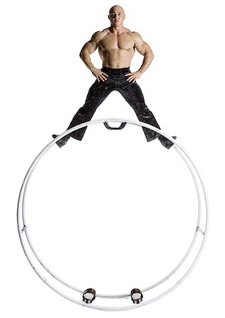 Male bodybuilder posing on top of German wheel Stock Photo - Premium Royalty-Free, Code: 640-01358055