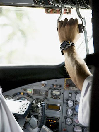 Rear view of a pilot operating the control panel in an airplane Stock Photo - Premium Royalty-Free, Code: 640-01358137
