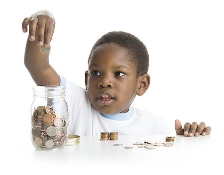 Close-up of a boy collecting coins in a jar Stock Photo - Premium Royalty-Free, Code: 640-01358144