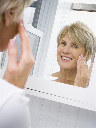 Portrait of a mature woman applying moisturizer on her face Stock Photo - Premium Royalty-Free, Code: 640-01358246