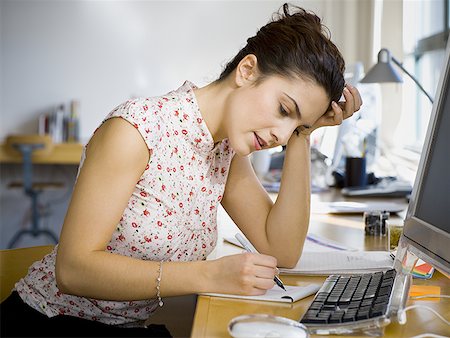 Profile of a young woman writing on a notepad in an office Stock Photo - Premium Royalty-Free, Code: 640-01359058