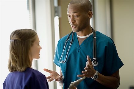 physician consulting backview - Close-up of a male doctor talking to a female doctor Stock Photo - Premium Royalty-Free, Code: 640-01359600