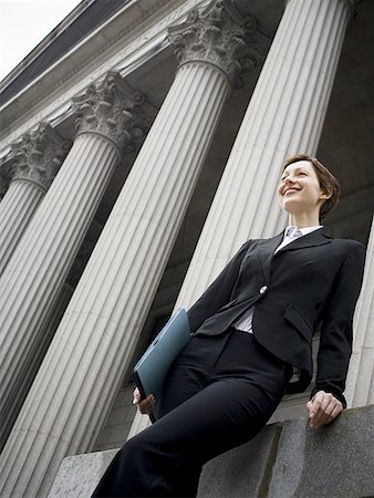 Low angle view of a female lawyer holding a file and smiling Stock Photo - Premium Royalty-Free, Code: 640-01359619