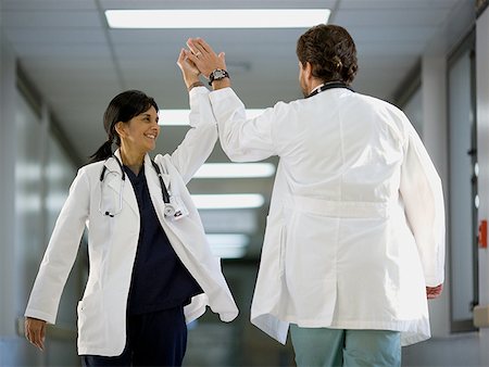 physician consulting backview - Rear view of a male doctor giving high-five to a female doctor Stock Photo - Premium Royalty-Free, Code: 640-01359633