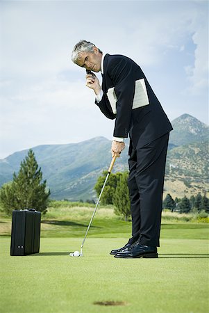 Profile of a businessman playing golf and talking on a mobile phone Stock Photo - Premium Royalty-Free, Code: 640-01350147