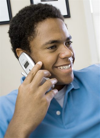 Close-up of a teenage boy talking on a mobile phone and smiling Stock Photo - Premium Royalty-Free, Code: 640-01350235