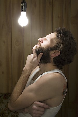 energía eléctrica - Man looking thoughtfully at light bulb Foto de stock - Sin royalties Premium, Código: 640-01350381