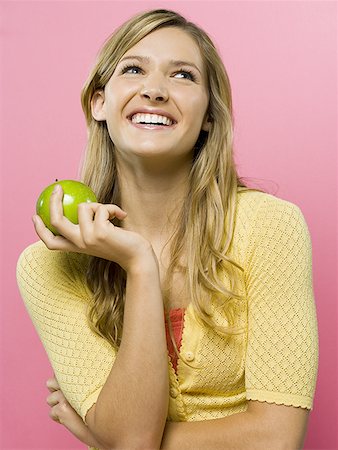 Woman smiling with green apple Stock Photo - Premium Royalty-Free, Code: 640-01351072