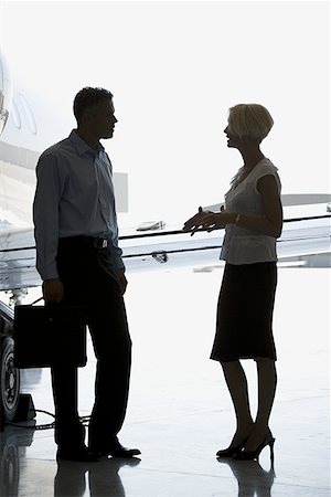 simsearch:640-01350298,k - Profile of a businesswoman and a businessman standing near an airplane and talking Stock Photo - Premium Royalty-Free, Code: 640-01351349