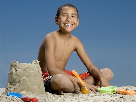 Portrait of a boy sitting beside a sand castle Foto de stock - Sin royalties Premium, Código: 640-01351466