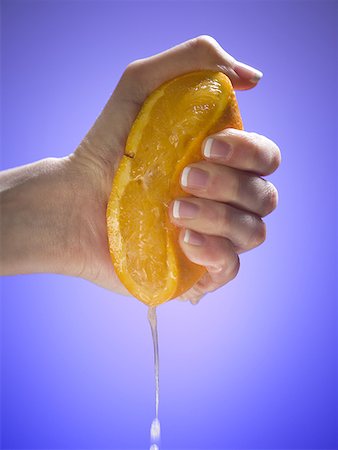 Close-up of a woman's hand squeezing an orange Stock Photo - Premium Royalty-Free, Code: 640-01351860