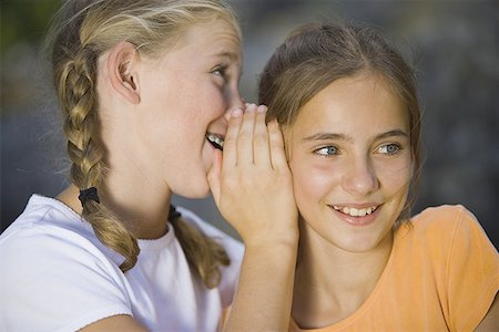 enigma - Close-up of a girl whispering into her friend's ear Stock Photo - Premium Royalty-Free, Code: 640-01352203