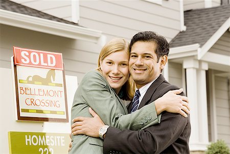 sold sign - Portrait d'un couple s'enlaçant devant la maison avec le signe ""Vendu"" Photographie de stock - Premium Libres de Droits, Code: 640-01353039