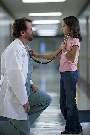 Profile of a girl checking a male doctor's heart beat with a stethoscope Stock Photo - Premium Royalty-Free, Code: 640-01353471