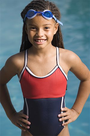 Portrait of a girl standing at a swimming pool and smiling Stock Photo - Premium Royalty-Free, Code: 640-01353482