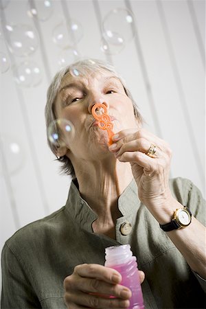 simsearch:640-02768330,k - Portrait of an elderly woman blowing bubbles with a bubble wand Stock Photo - Premium Royalty-Free, Code: 640-01364093