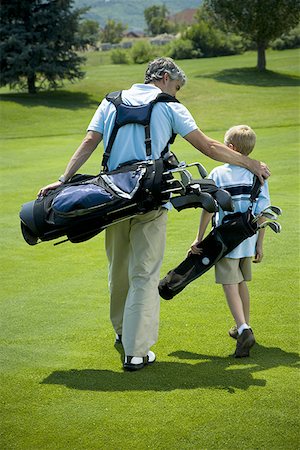 Rear view of a man carrying a golf bag with his son Stock Photo - Premium Royalty-Free, Code: 640-01364159