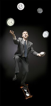 Businessman standing on hourglass and juggling with clocks Stock Photo - Premium Royalty-Free, Code: 640-01364218