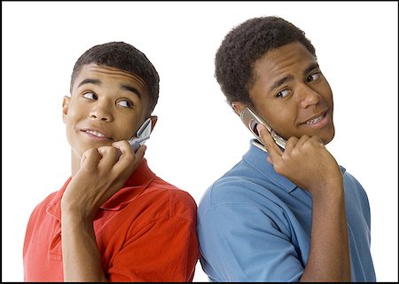 Close-up of two young men standing back to back talking on mobile phones Stock Photo - Premium Royalty-Free, Code: 640-01364550