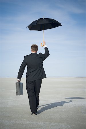 future of the desert - Rear view of a businessman walking and holding an umbrella Stock Photo - Premium Royalty-Free, Code: 640-01365304