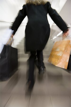 female rear end - Rear view of a woman running up a staircase with shopping bags Stock Photo - Premium Royalty-Free, Code: 640-01366322