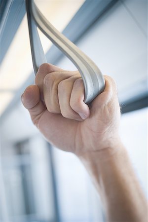 Close-up of a man's hand holding a handle on a commuter train Stock Photo - Premium Royalty-Free, Code: 640-01360044