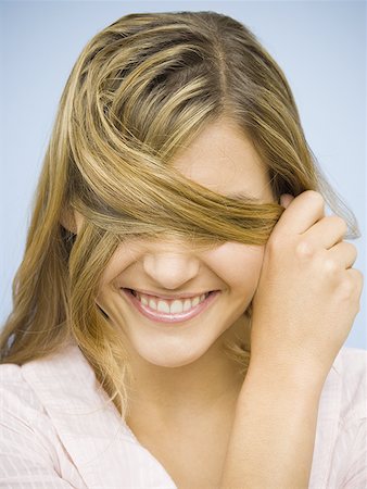 strand - Closeup of smiling woman hiding eyes with hair Stock Photo - Premium Royalty-Free, Code: 640-01360108