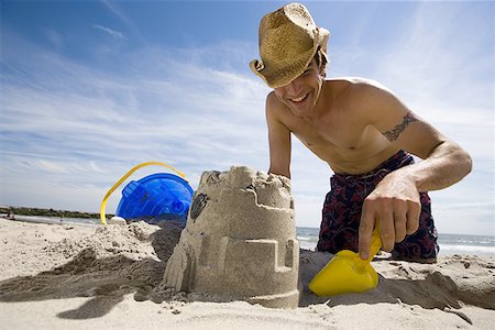 saving (keeping) - Low angle view of a young man digging sand on the beach Stock Photo - Premium Royalty-Free, Code: 640-01360316