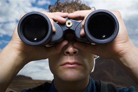 enigma - Close-up of a young man looking through binoculars Stock Photo - Premium Royalty-Free, Code: 640-01360653