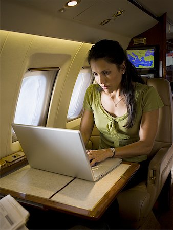 Woman working on a laptop in an airplane Stock Photo - Premium Royalty-Free, Code: 640-01360961
