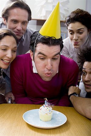 simsearch:640-01350537,k - Man wearing a birthday hat and blowing out a candle Stock Photo - Premium Royalty-Free, Code: 640-01360963