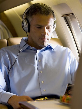 flew - A businessman listening to music on headphones in an airplane Stock Photo - Premium Royalty-Free, Code: 640-01361035