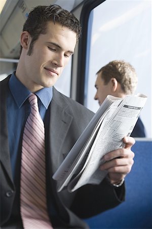Close-up of a young man reading a newspaper on a commuter train Stock Photo - Premium Royalty-Free, Code: 640-01361118
