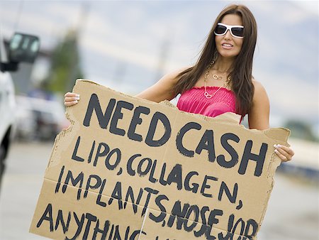Woman standing on side of road soliciting cash Stock Photo - Premium Royalty-Free, Code: 640-01361745