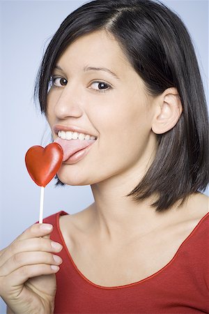 Portrait of a young woman licking a lollipop Stock Photo - Premium Royalty-Free, Code: 640-01362016