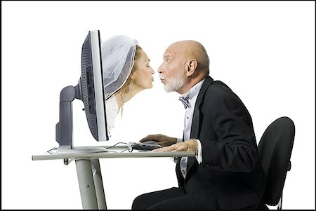 Profile of a senior man kissing a senior woman emerging from a computer monitor Stock Photo - Premium Royalty-Free, Code: 640-01362279