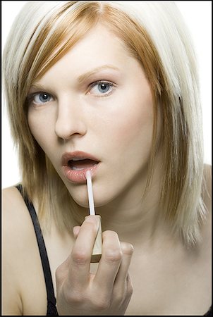 Portrait of a young woman applying lip gloss Stock Photo - Premium Royalty-Free, Code: 640-01362332