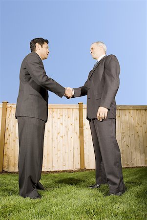 Low angle view of two businessmen shaking hands Stock Photo - Premium Royalty-Free, Code: 640-01362364