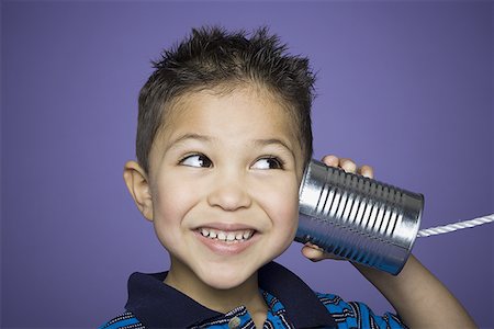Close-up of a boy listening to a tin can phone Stock Photo - Premium Royalty-Free, Code: 640-01362391