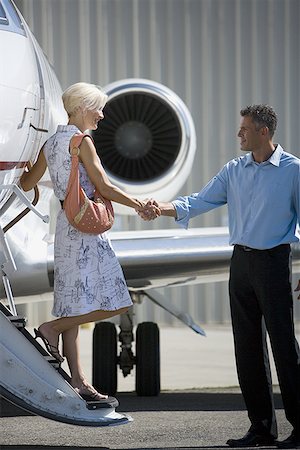 simsearch:640-01350298,k - Businessman shaking hands with a businesswoman stepping down from an airplane Stock Photo - Premium Royalty-Free, Code: 640-01362571