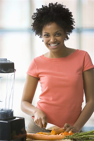 Portrait of a young woman cutting vegetables and smiling Stock Photo - Premium Royalty-Free, Code: 640-01362836