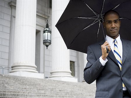 simsearch:640-02767805,k - Portrait of a male lawyer standing in front of a courthouse and holding an umbrella Stock Photo - Premium Royalty-Free, Code: 640-01363650